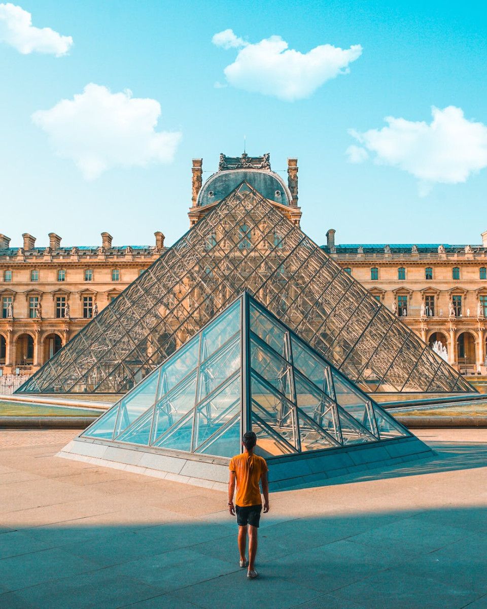 man standing in front of louvre museum of paris